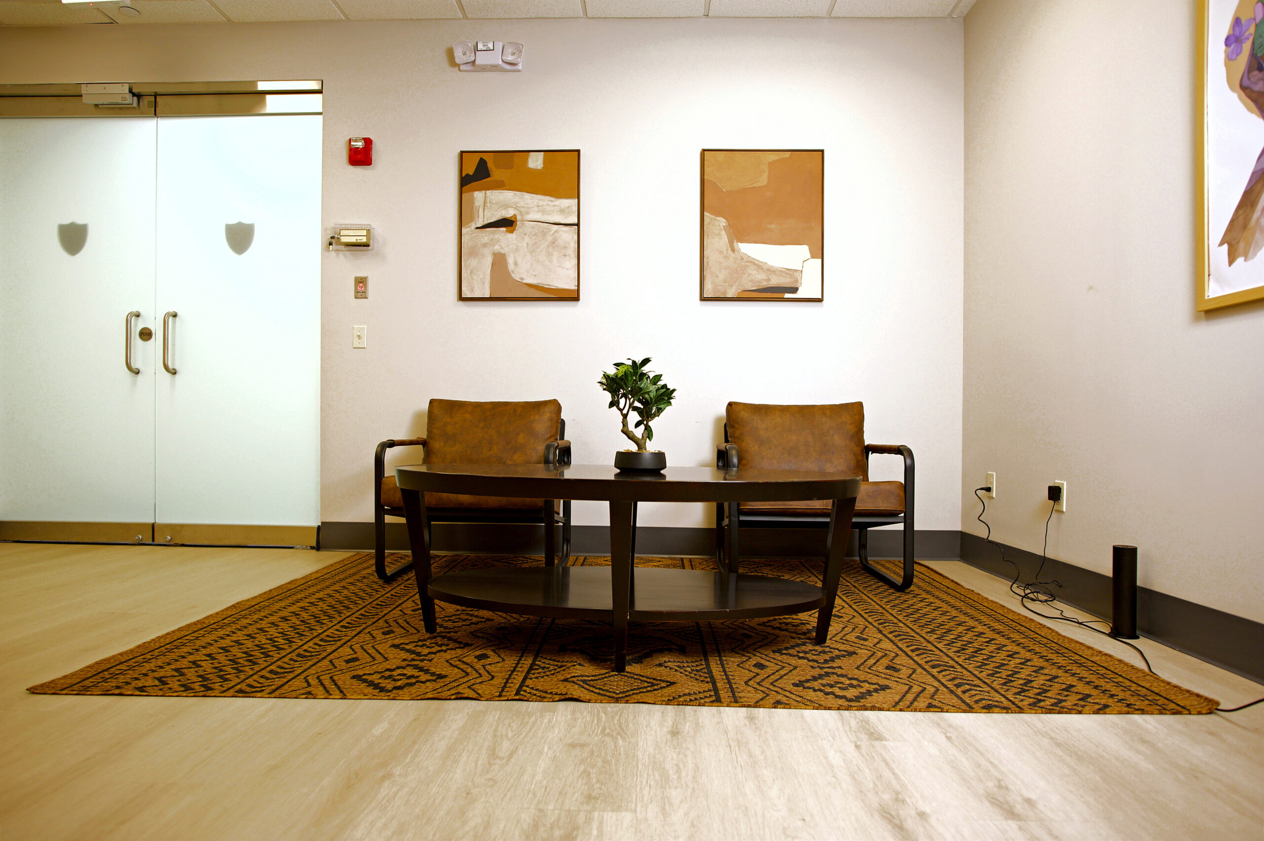 Seating area with two armchairs, a coffee table and framed art at Holgate Mental Health in Montvale, NJ