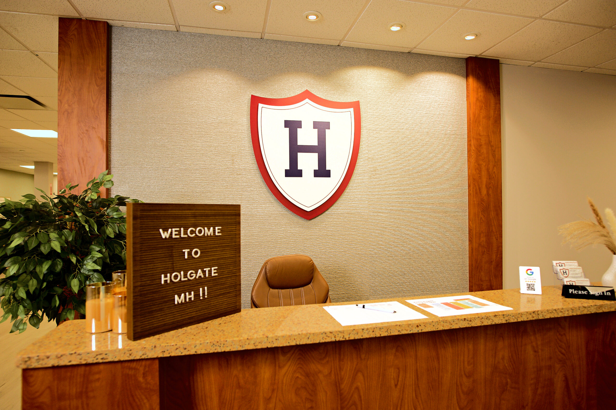 "Welcome to Holgate MH" sign on the reception counter beneath the Holgate shield logo
